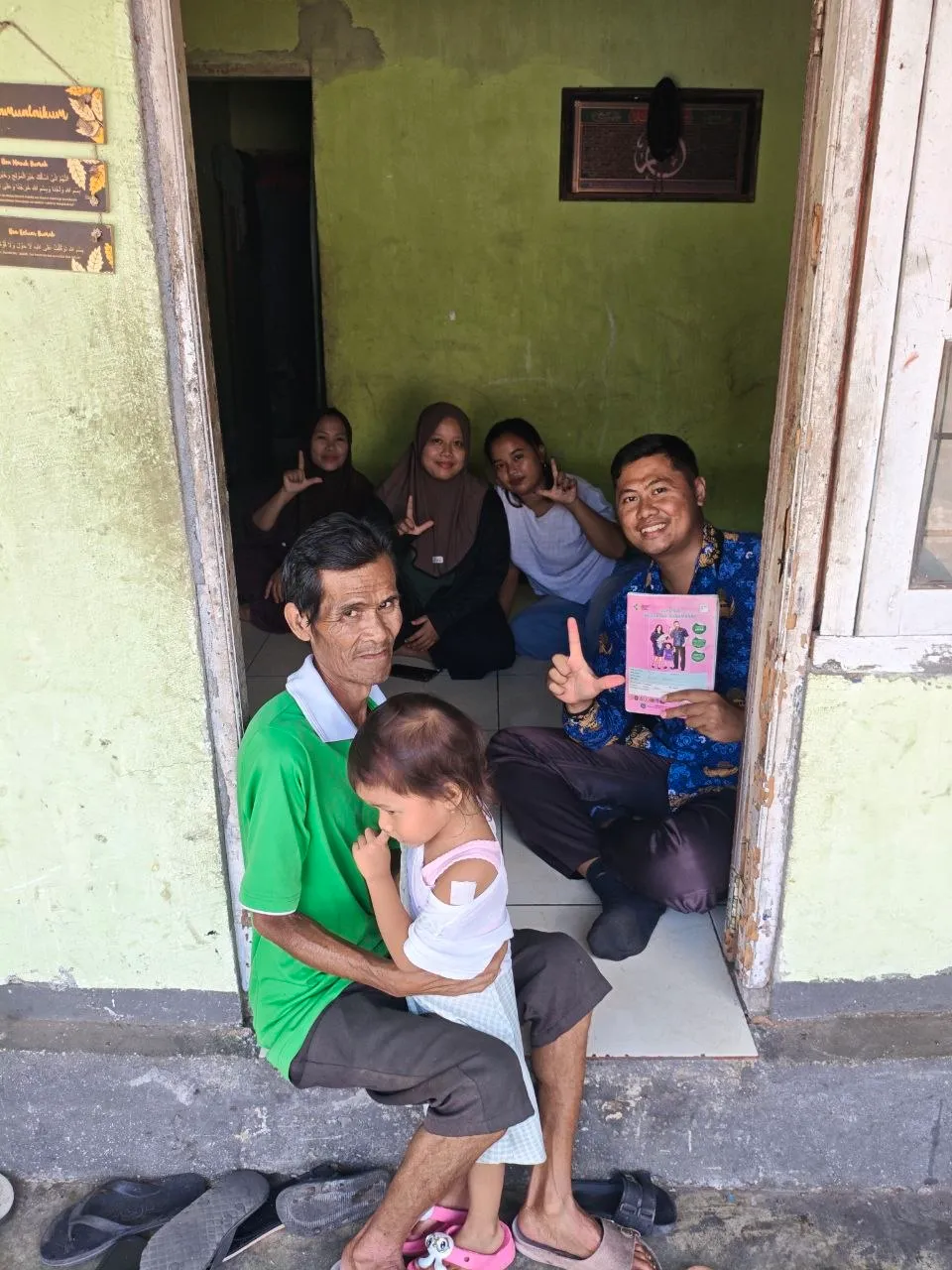Petugas bersama sebuah keluarga di depan pintu rumah