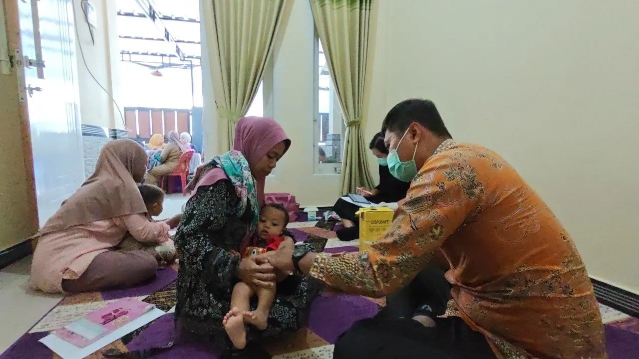 Petugas mengimunisasi bayi di rumah warga