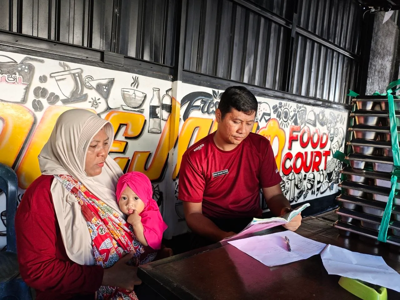 Petugas berbincang dengan seorang ibu yang menggendong bayinya