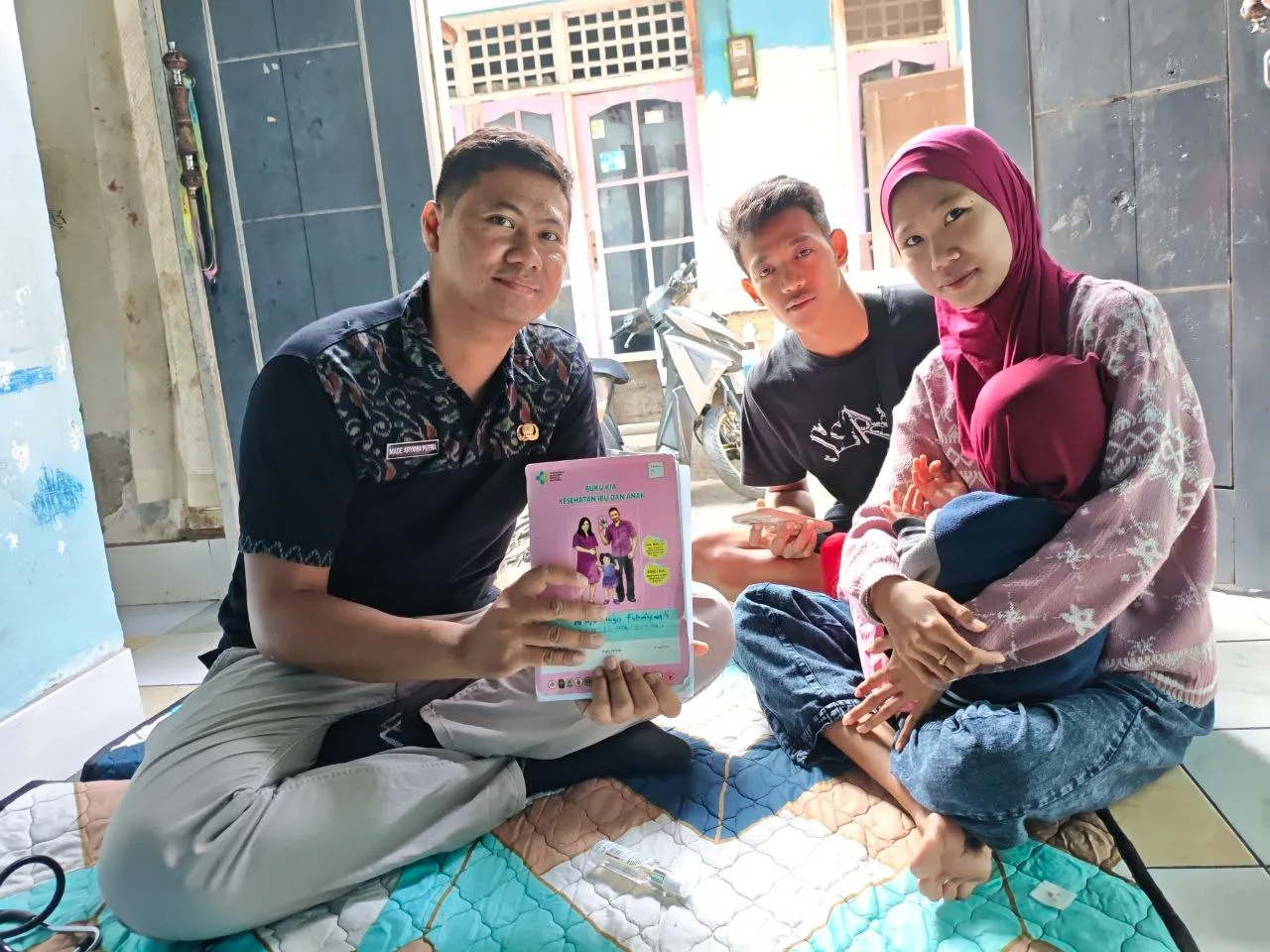Petugas menunjukkan buku panduan kepada sebuah keluarga