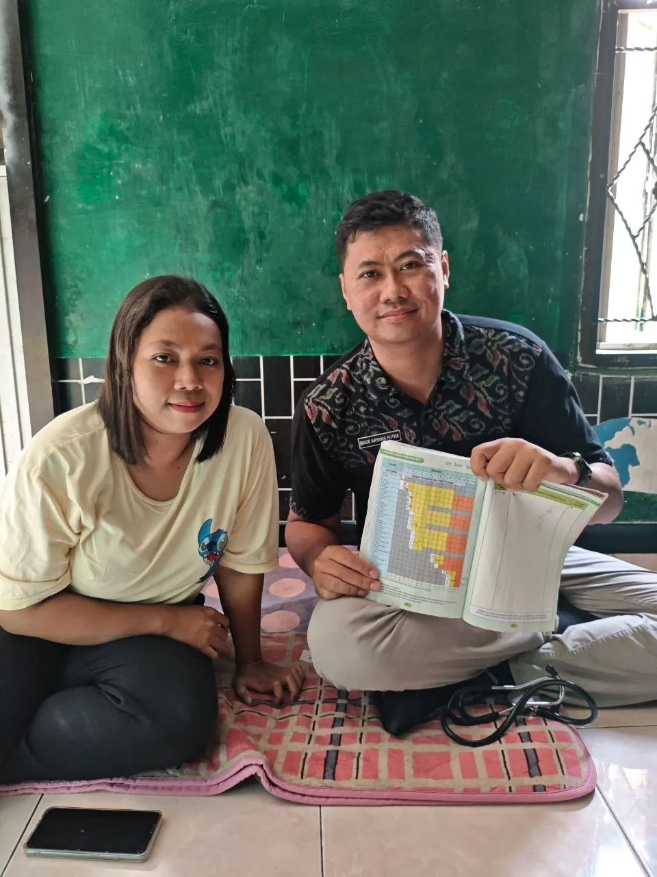 Petugas dan seorang ibu membaca lembar informasi