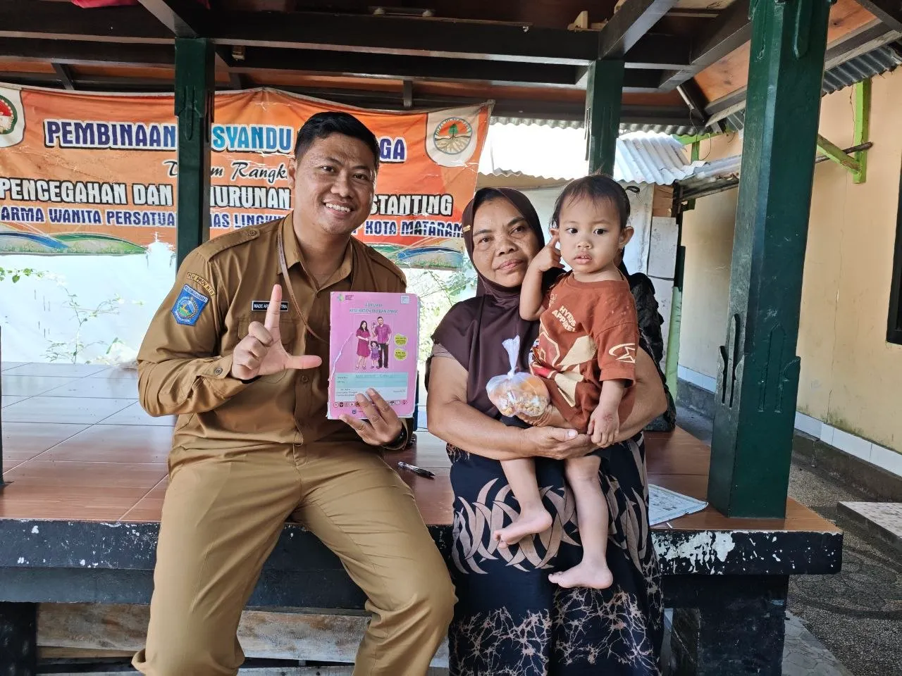 Petugas berfoto bersama ibu dan anaknya di posyandu