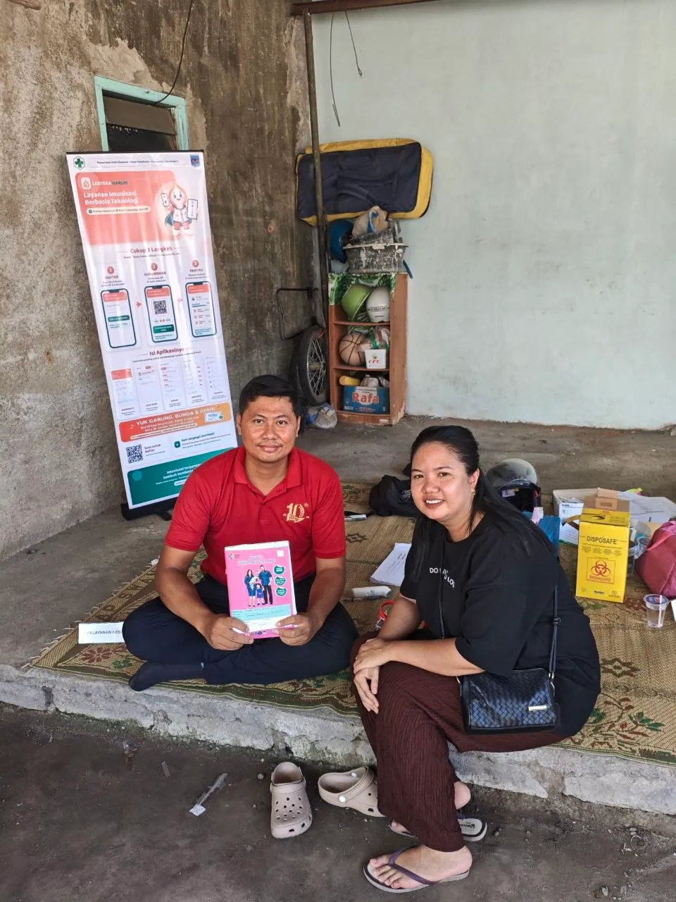 Petugas dan seorang ibu duduk di depan banner LENTERA HARUM